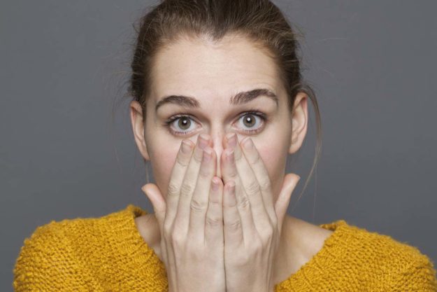 causes-of-bad-breath woman covering her mouth to prevent the cause of bad breath