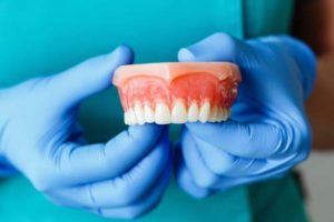 dentist holding a pair of upper dentures