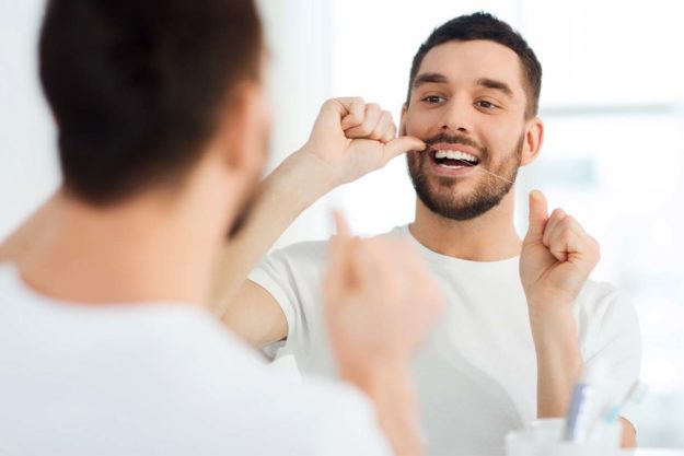 how-to-prevent-teeth-shifting (3) Man flossing to prevent teeth shifting