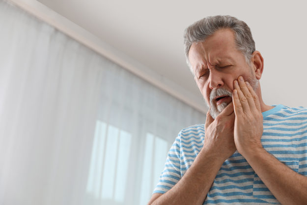 I have a dental emergency man holding jaw thinking I have a dental emergency