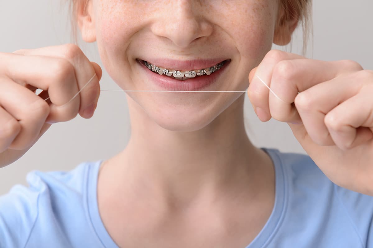 a young woman trying to floss with braces