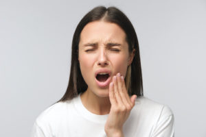 a woman feeling the pain of Impacted Teeth